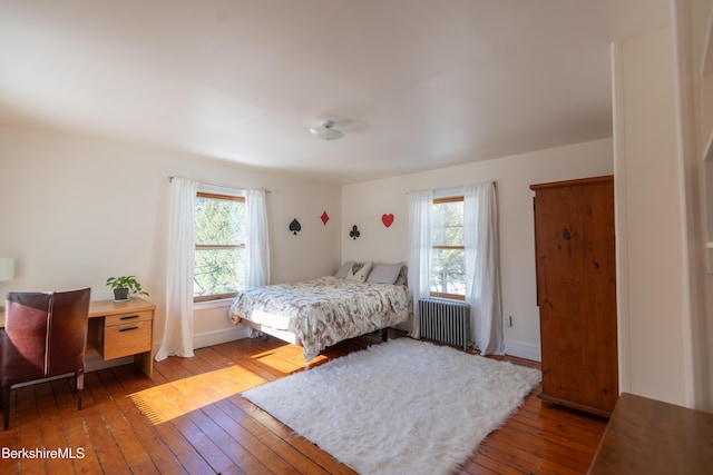 bedroom with multiple windows, radiator, and light hardwood / wood-style flooring