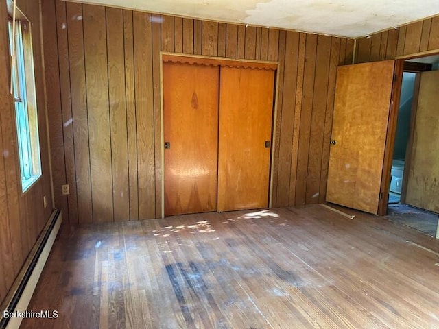 425 Barbour St, North Adams, MA 01247 - unfurnished bedroom with a baseboard heating unit, hardwood / wood-style flooring, wooden walls, and a closet