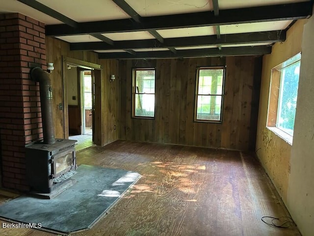 425 Barbour St, North Adams, MA 01247 - unfurnished living room with plenty of natural light, a wood stove, beamed ceiling, and wood walls