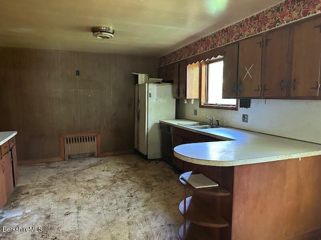 425 Barbour St, North Adams, MA 01247 - kitchen featuring radiator, light countertops, freestanding refrigerator, wood walls, and a peninsula