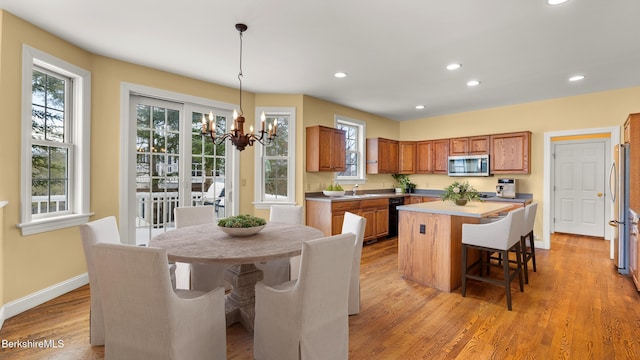 kitchen with light wood finished floors, stainless steel microwave, brown cabinets, a kitchen breakfast bar, and a center island