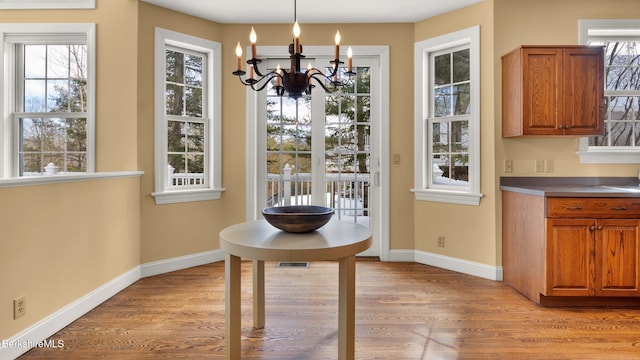 unfurnished dining area with baseboards, a notable chandelier, visible vents, and light wood finished floors