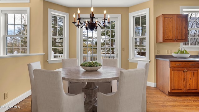 dining room with light wood finished floors, plenty of natural light, an inviting chandelier, and baseboards