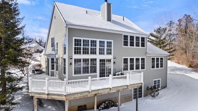 snow covered back of property featuring a chimney and a wooden deck