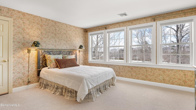 carpeted bedroom with wallpapered walls, visible vents, and baseboards