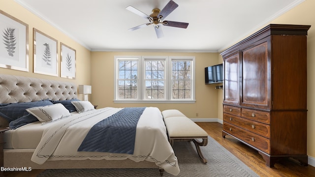 bedroom with ornamental molding, wood finished floors, a ceiling fan, and baseboards