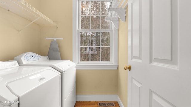 clothes washing area featuring laundry area, baseboards, visible vents, wood finished floors, and independent washer and dryer