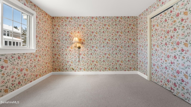 empty room with wallpapered walls, baseboards, and carpet flooring