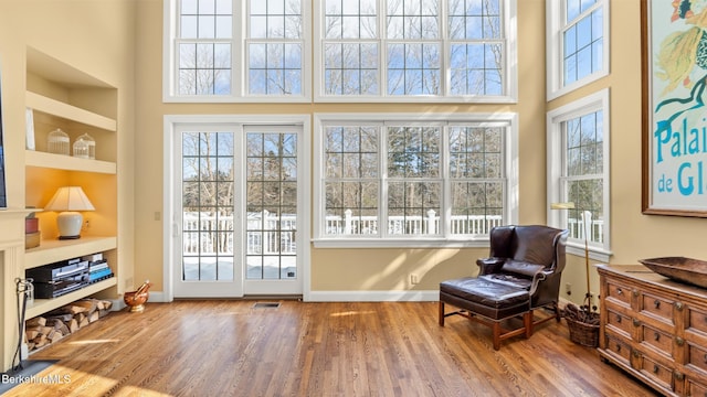 living area featuring built in features, baseboards, visible vents, and wood finished floors