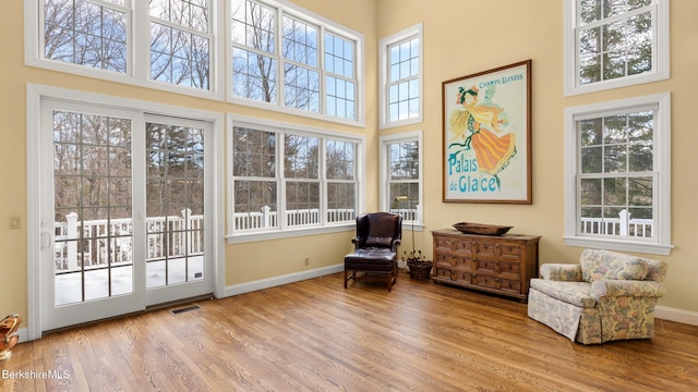 living area featuring a towering ceiling, baseboards, and wood finished floors