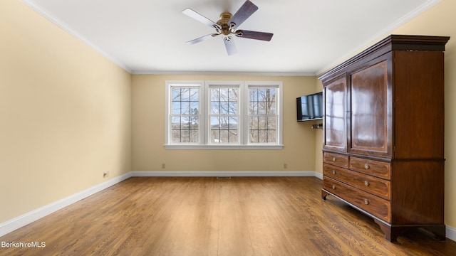 unfurnished bedroom with ornamental molding, wood finished floors, a ceiling fan, and baseboards