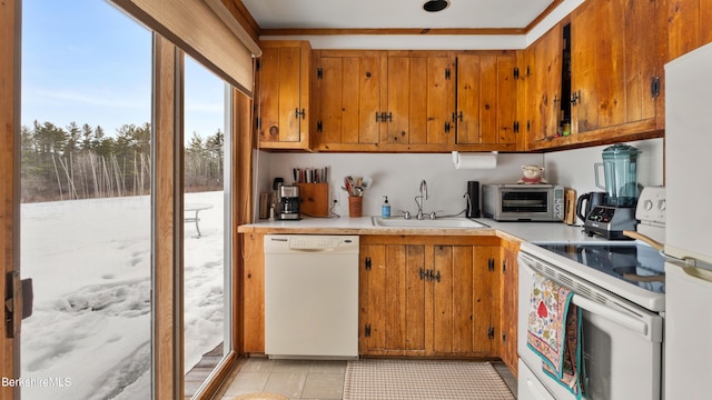 kitchen with white appliances, a toaster, brown cabinetry, light countertops, and a sink