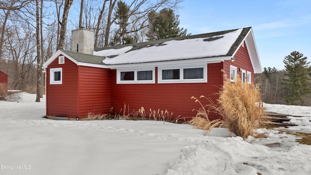 snow covered property with a chimney