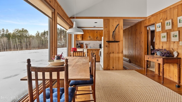 dining room with high vaulted ceiling, wood walls, and wood finished floors