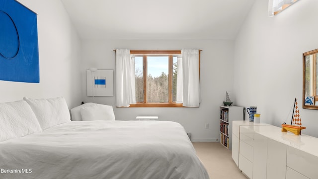 bedroom featuring light carpet, lofted ceiling, and baseboards