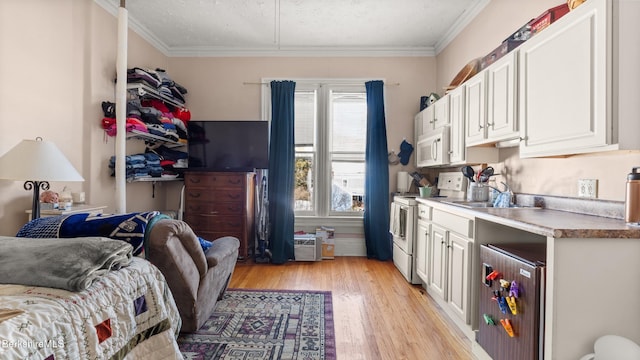 kitchen featuring wine cooler, ornamental molding, white cabinets, a sink, and white appliances