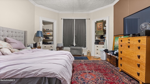 bedroom featuring ornamental molding, radiator, a textured ceiling, and wood finished floors