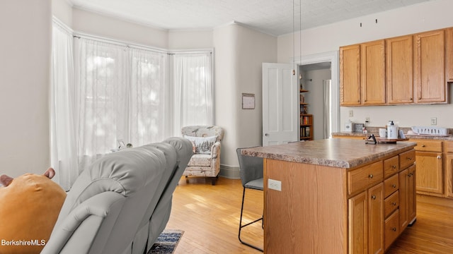 kitchen featuring open floor plan, a kitchen bar, a center island, and light wood-style floors