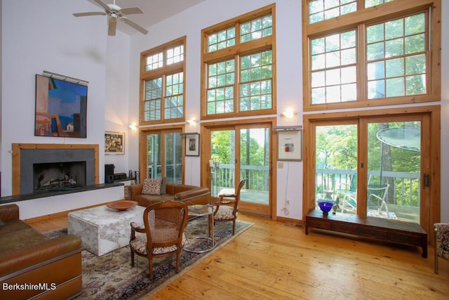 living room featuring ceiling fan, light wood-type flooring, and a towering ceiling