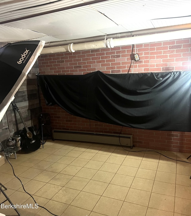 interior space with a baseboard radiator and brick wall