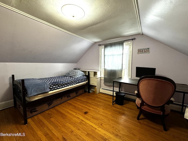 bedroom with a textured ceiling, hardwood / wood-style flooring, lofted ceiling, and a baseboard heating unit