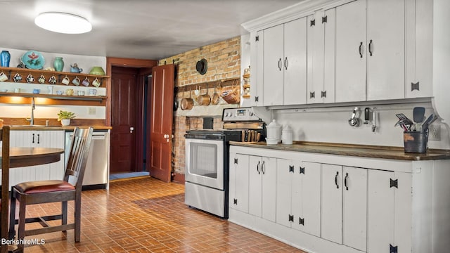 kitchen featuring sink, white cabinetry, stainless steel appliances, and brick wall