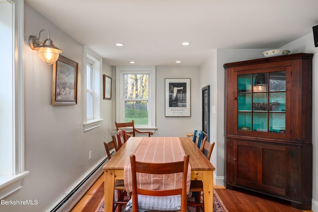 dining area with dark wood-type flooring and a baseboard heating unit