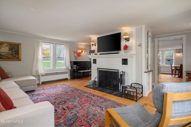 living room with radiator, crown molding, a fireplace, and a wealth of natural light