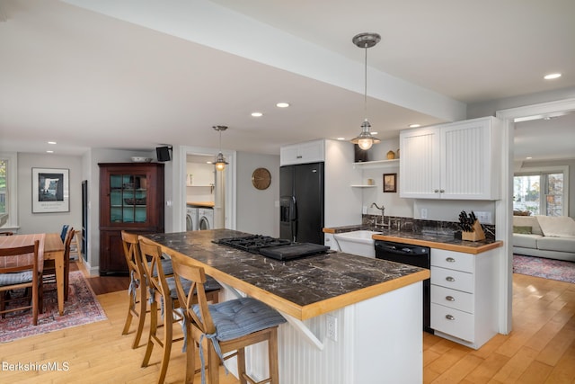 kitchen featuring a breakfast bar, white cabinets, black appliances, and decorative light fixtures