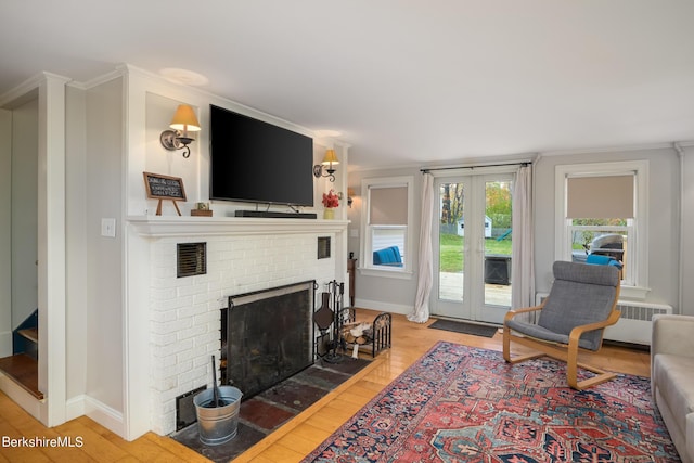 living room featuring a fireplace, light wood-type flooring, and ornamental molding