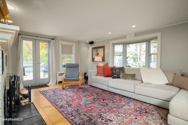 living room featuring radiator, french doors, ornamental molding, and light wood-type flooring