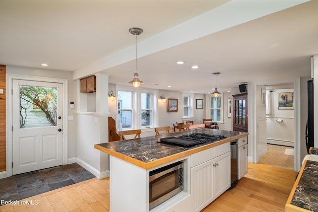 kitchen with stainless steel appliances, a kitchen island, a baseboard radiator, white cabinetry, and hanging light fixtures