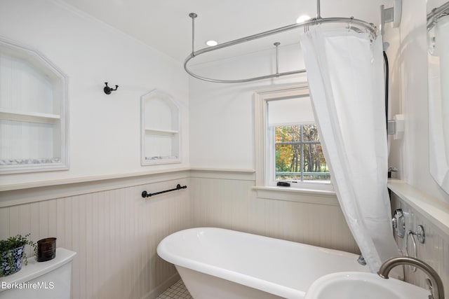 bathroom featuring a tub to relax in, crown molding, sink, and toilet