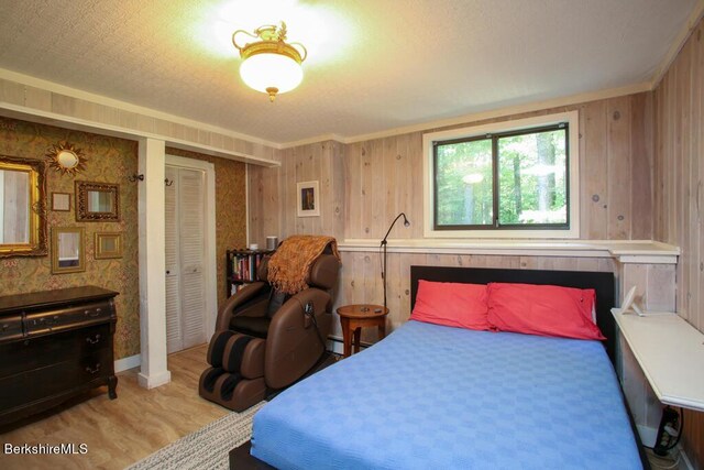 bedroom featuring wood walls, wood finished floors, a baseboard radiator, ornamental molding, and a closet