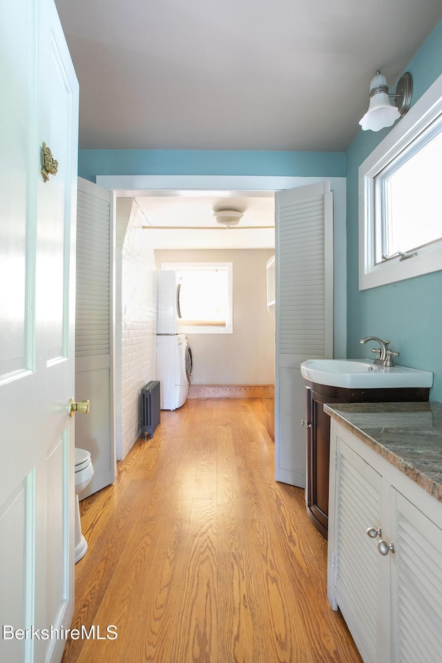 311 N Plain Rd, Great Barrington, MA 01236 - bathroom with stacked washer / drying machine, vanity, radiator, toilet, and wood finished floors