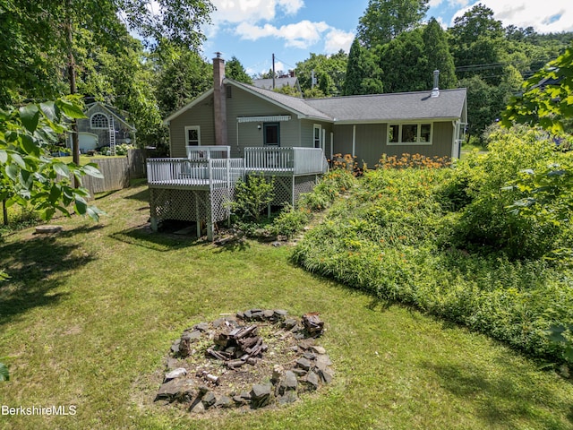 back of property with a yard, a fire pit, and a wooden deck