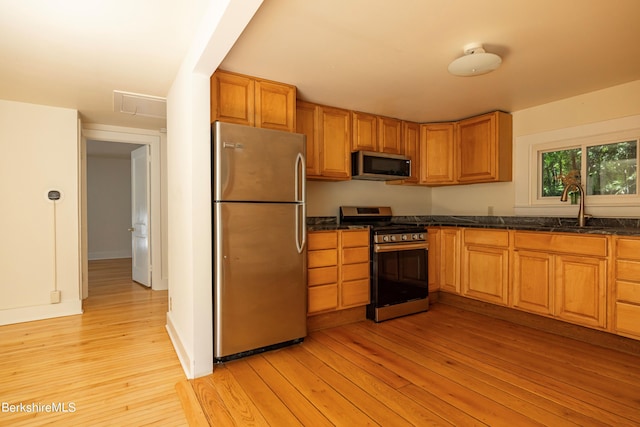 kitchen with sink, stainless steel appliances, and light hardwood / wood-style floors