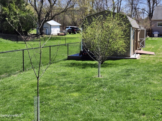 view of yard featuring fence, an outbuilding, and a shed
