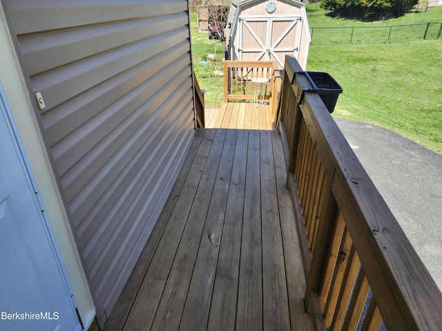 wooden terrace with a yard, fence, a storage shed, and an outdoor structure