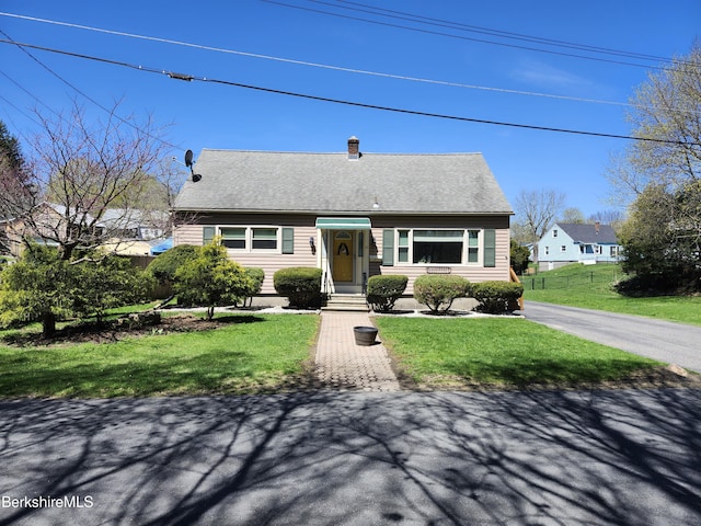view of front of home with fence, a chimney, and a front yard