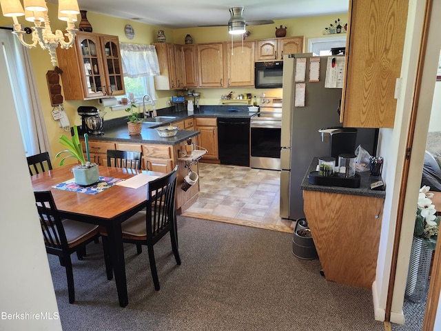 kitchen featuring dark countertops, a sink, ceiling fan with notable chandelier, stainless steel appliances, and glass insert cabinets