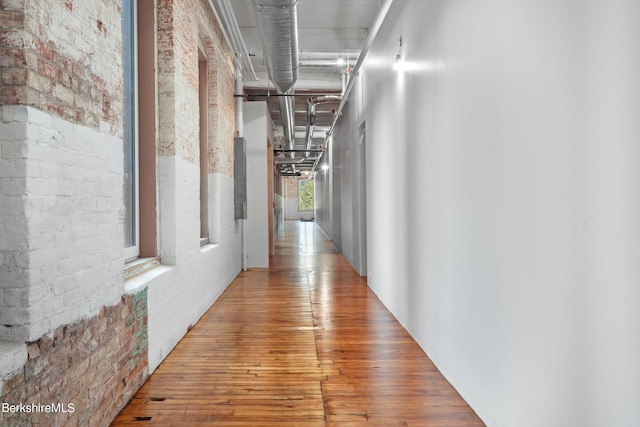 hall with hardwood / wood-style flooring and brick wall