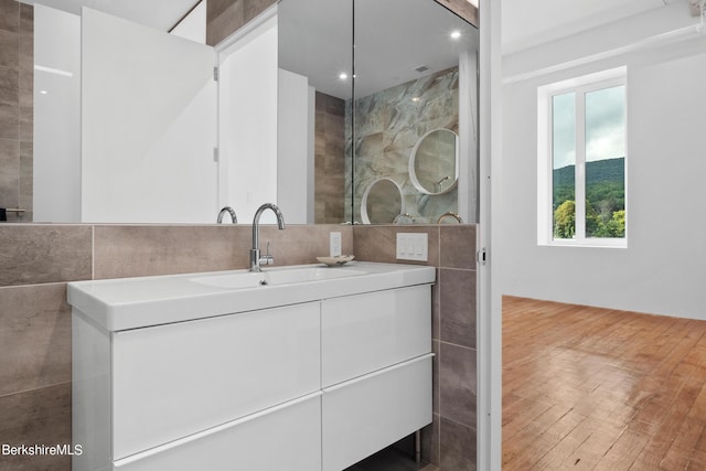 bathroom featuring vanity, wood-type flooring, and tile walls