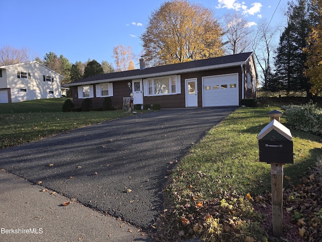 ranch-style home with a garage, driveway, a chimney, and a front lawn