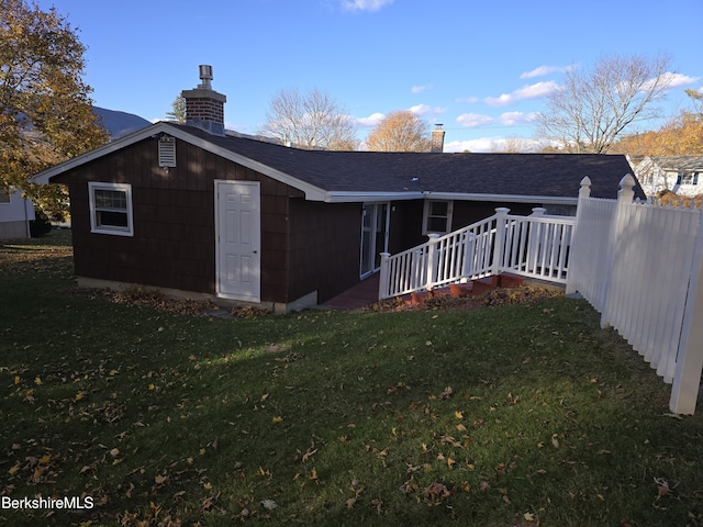 back of house with a chimney, a lawn, and a wooden deck