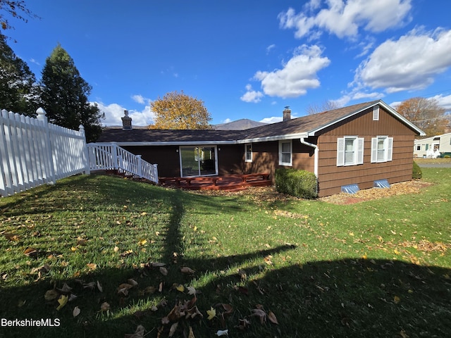 rear view of house with fence and a lawn