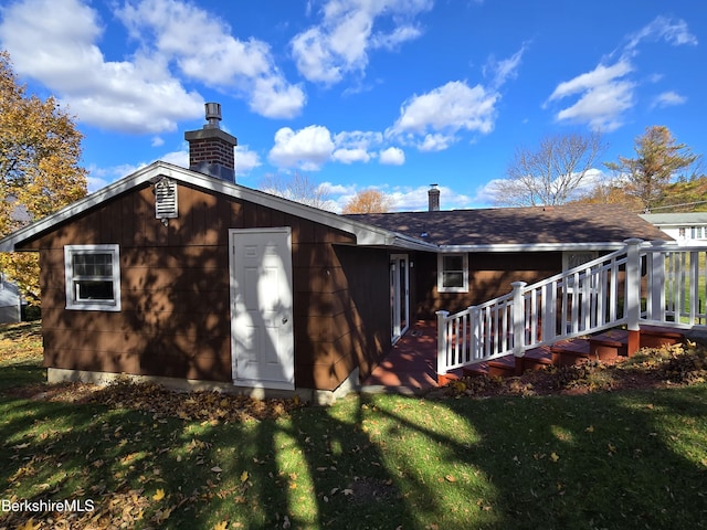 rear view of property with a deck, a yard, and a chimney