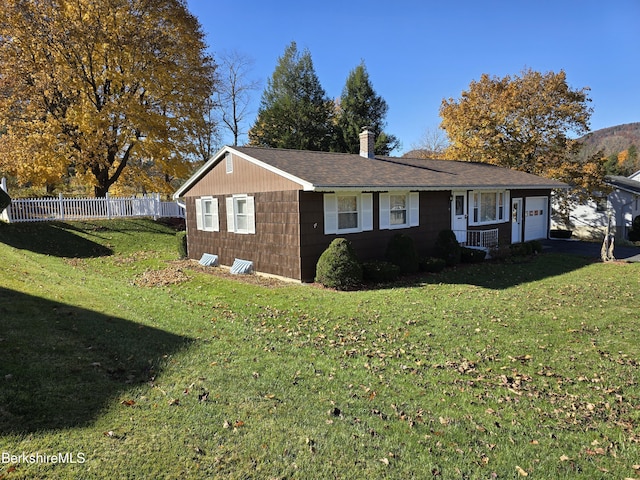 view of front of property with an attached garage, a shingled roof, fence, a lawn, and a chimney