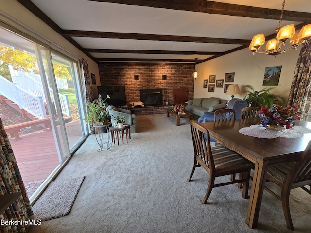 dining area with a chandelier, beam ceiling, carpet flooring, and a brick fireplace