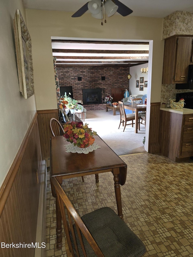 dining area with a brick fireplace and ceiling fan